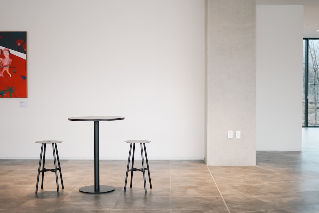 a-table-and-two-stools-in-a-room-oqohl975bwk